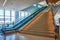 Bottom to top view of generic stairs ascending with two escalators on left side and distant elevator