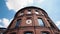 Bottom view of beautiful building with round architecture on background blue sky. Action. Round old red brick building