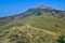 Bottom view of beautiful landscape with green hill covered dry yellow green grass, high mountain with peak in blue sky, Crimea