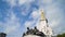 Bottom view of beautiful monument with sculptures on blue sky background. Action. Monument with human sculptures in