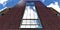 Bottom view of the catholic church huge window against the blue cloudy sky. Dark red brick facade finishing. 3d rendering