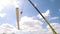 Bottom view of the crane carrying large wooden beam on blue cloudy sky background. Clip. Detail of wooden frame of