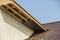 Bottom view detail of new modern house cottage corner with stucco walls, brown shingled roof and unfinished siding installation on