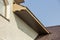 Bottom view detail of new modern house cottage corner with stucco walls, brown shingled roof and unfinished siding installation o