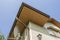 Bottom view detail of new modern house top with decorative lamp and satellite dish on stucco walls, plastic attic window, gutter p