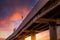 Bottom view of elevated concrete highway. Overpass concrete road. Road flyover structure. Motorway with red sunrise sky. Concrete