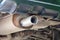 Bottom view of the exhaust pipe of the car, rusty, dusty parts and fixtures