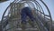 Bottom view of factory worker in blue uniform climbing down the ladder on huge storage tower. Unrecognizable Caucasian