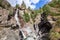 Bottom view of flowing Lillaz waterfall Cascate di Lillaz and granite karst rocks with evergreen trees