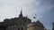 Bottom view of Mont Saint Michel castle in France on blue cloudy sky background with flying seaguls. Action. Beautiful