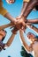 bottom view of multiracial young friends holding hands together with blue sky