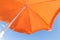 Bottom view of orange parasol against a blue sky