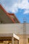 Bottom view of the roof of the industrial pavilion, fence and stairs over the blue sky and clouds