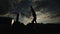 Bottom view of silhouette of muscular young sportsman walking on hands on parallel bars during street workout at sunset