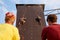 Bottom view of two young women climbers insured by men on rope belay harness approaching to finishing point on the speed