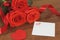 Bouguet of red roses tied with red satin ribbon, a souvenir in the for of heart of red color and a small piece of paper painted h.