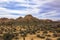 Boulder formations in Joshua Tree National Park, California. Mountain with the condensation trail, or contrail, that looks like a