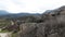 Boulders expanse at the foots of mountain range. Shot. Aerial view of a wild valley covered by stones, greenery and