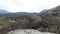 Boulders expanse at the foots of mountain range. Shot. Aerial view of a wild valley covered by stones, greenery and