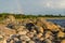 Boulders, forest, shore, evening light, sunset, clouds, blue sky and rainbow on the Baltic Sea