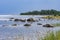 Boulders, forest, shore, evening light, sunset, clouds, blue sky and rainbow on the Baltic Sea.