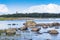 Boulders, forest, shore, evening light, sunset, clouds, blue sky and rainbow on the Baltic Sea.