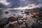 Boulders, forest, shore, evening light, sunset, clouds, blue sky and rainbow on the Baltic Sea.