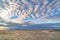 Boundless blue sky with gray and white clouds over a vast sandy shore