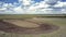 Boundless field with red tractor and birds fly over furrow