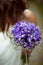 A bouqet of violet crocuses is held by a bride