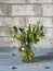 Bouquet of answered dandelions in a glass jug on a turquoise plank tray