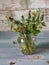 Bouquet of answered dandelions in a glass jug on a turquoise plank tray, side view from close range