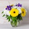 A bouquet of autumn flowers in a glass vase on a light wooden table. Floral design, element decoration in a rustic style. Still