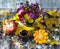 A bouquet of autumn flowers in a retro pot, orange pumpkins, autumn leaves, a vintage cup. Late autumn, November, the first snow.