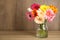 Bouquet of beautiful bright gerbera flowers in glass vase on table against wooden background