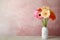 Bouquet of beautiful bright gerbera flowers in vase on marble table against color background.