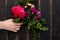 Bouquet of beautiful flowers for the holiday in a female hand on a wooden background