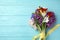 Bouquet of beautiful spring flowers on blue table, top view. Space for text