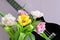 A bouquet of beautiful tulips on a lilac background and a fragment of a musical instrument ukulele.