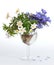 A bouquet of blue hepatica and white anemone in a glass goblet.