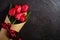 Bouquet with bow-knot ribbon of red tulip flowers on textured black background