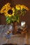 A bouquet of bright sunflowers in a clay jug, books, a glass of milk and a bowl of cookies