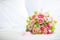 A bouquet bunch of colorful fake fabric flowers on white bed cover with copy spce