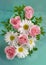 Bouquet of camomiles and roses on white green background
