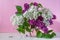 Bouquet of colorful lilac flowers in a glass vase on a pink background