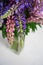 Bouquet of colorful lupines in a glass vase on white. Copy space