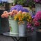 Bouquet of dahlias in a galvanized bucket stands on a chair near the entrance to the store.