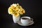 Bouquet of daisies in a vase and a cup of hot coffee / tea on a black background