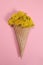 Bouquet of dandelion flowers in an ice cream waffle cone on a pink background. Vertical Orientation