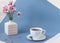 A bouquet of delicate pink flowers in a white vase with a Cup of fragrant tea on a blue background, close-up, place for the